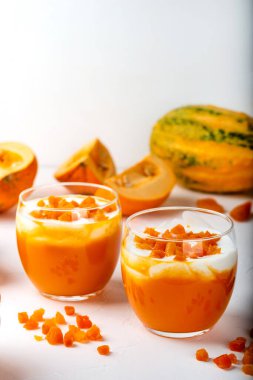 Balkabağı çiğ tatlı. Beyaz arka planda yoğurtlu balkabağı püresi ve kurumuş kayısılar. Sonbahar ev yapımı sağlıklı diyet yemekleri. Yakın plan..