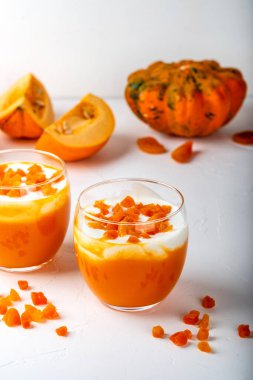 Balkabağı çiğ tatlı. Beyaz arka planda yoğurtlu balkabağı püresi ve kurumuş kayısılar. Yakın plan..