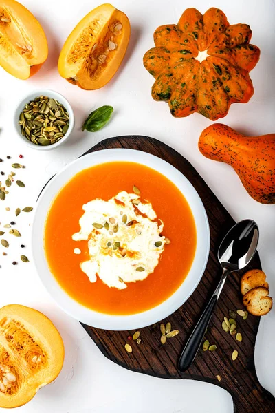 Pumpkin cream soup with milk and pumpkin seeds in a white bowl on the white background. Close-up. Top view. — Stock Photo, Image