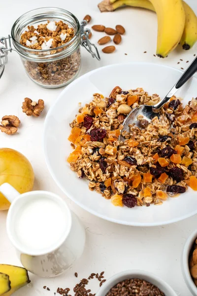 Гранола мюсли завтрак с молоком, сушеные абрикосы, клюква, миндаль и семена льна в миске на белом фоне. Здоровый завтрак из хлопьев . — стоковое фото