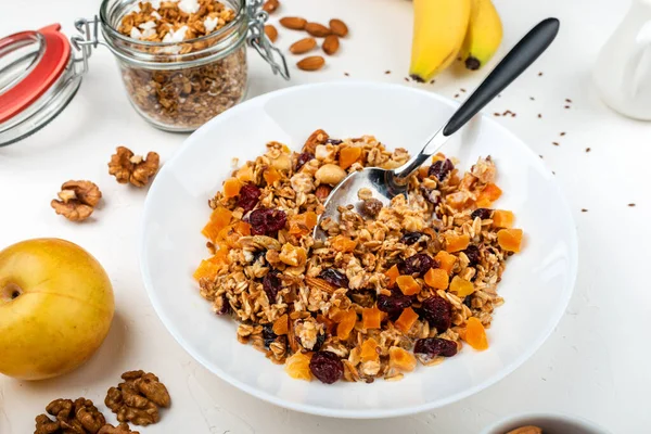 Гранола мюсли завтрак с молоком, сушеные абрикосы, клюква, миндаль и семена льна в миске на белом фоне. Здоровый завтрак из хлопьев . — стоковое фото