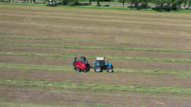 Una rotopressa scarica una balla di grano fresco durante la raccolta vista aerea. — Video Stock