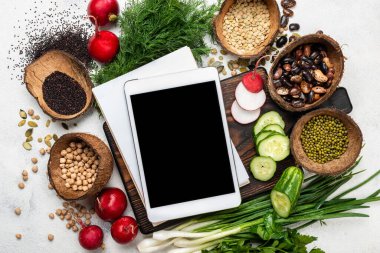 Tablet bilgisayar sebzeleri sebzeler yeşil fasulyeler doğrama tahtasının üstünde..