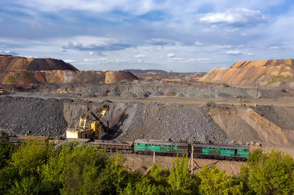 Cargo train carrying iron ore on the opencast mining quarry