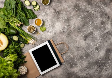 Tablet bilgisayar kağıt alışveriş çantası farklı sebzeler ve otlar.