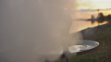 Gün batımının arka planında nehrin yanında bir kase nargile. Yavaş çekim