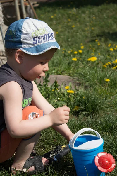 a boy and watering can play outdoor