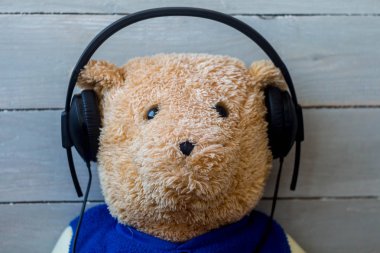 ahşap arka plan üzerinde kulaklık bir oyuncak ayı