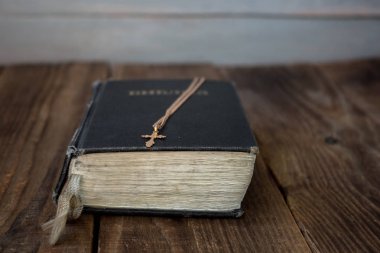 bir İncil ve ahşap zemin üzerine altın haçı
