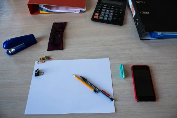 desk with paper pencils phone calculator glasses