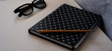masanın üzerine kalem ve defter gözlük