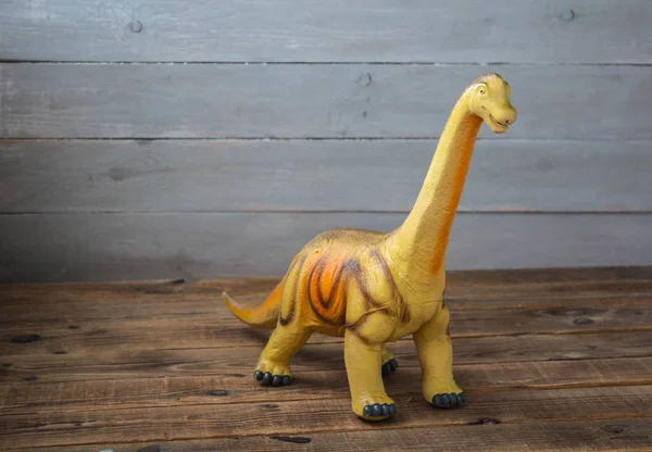 Un grande giocattolo per bambini dinosauro su uno sfondo di legno — Foto Stock