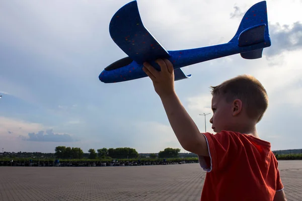Ein Junge spielt mit einem Flugzeug auf der Straße — Stockfoto