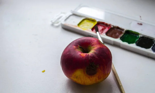Червоне яблуко і акварельна фарба і пензлик на білому тлі — стокове фото