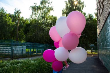 bir çocuk elinde renkli balonlar bir sürü tutar