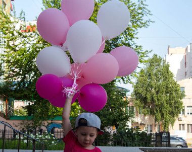 çocuk elinde renkli balonlar bir sürü tutar