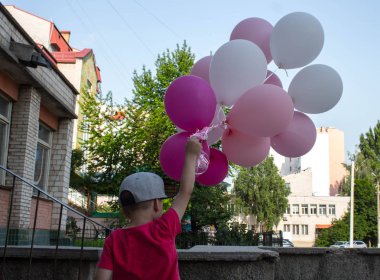 bir çocuk elinde renkli balonlar bir sürü tutar