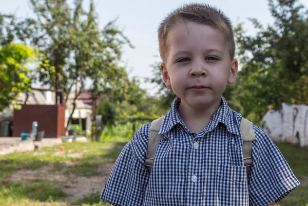 Piękny mały chłopiec na podwórku z plecakiem — Zdjęcie stockowe