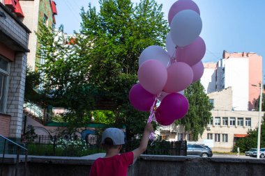 çocuk elinde renkli balonlar bir sürü tutar