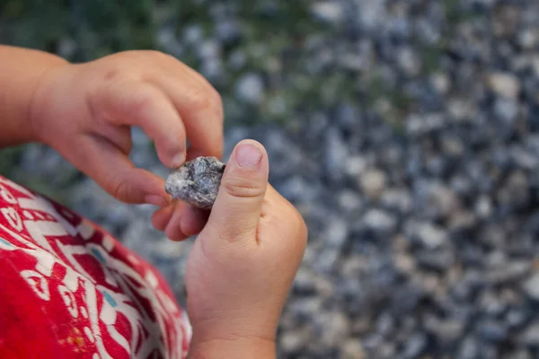 Ένα μικρό παιδί παίζει με πέτρες βότσαλο στο χέρι Εικόνα Αρχείου