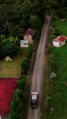 Dağların ortasındaki bir ormanın kırsal bir yolundaki arabanın sinematik insansız hava aracı görüntüsü.