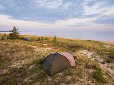 Sakin bir sahil şeridinin kumlu kumlu kumullarına kurulmuş kamp çadırları doğanın vahşi doğasında huzurlu bir geri çekilme imkanı sunuyor..