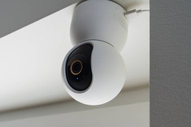 İç mekan güvenlik kameraları için tavana monte edilmiş mavi gösterge ışığı olan modern beyaz bir ev kamerası..