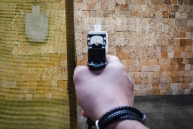 Hedefe kırmızı nokta görüşlü modern bir tabancayı hedef alan bir adamın eline ait birinci şahıs bakış açısı.