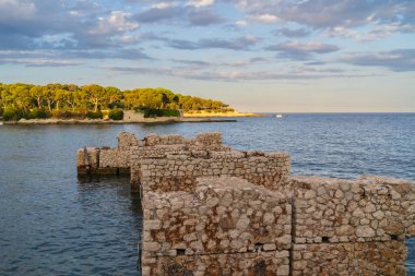 Akdeniz kıyısındaki tarihi taş köprü kalıntılarının manzarası güzel bir günbatımında Fransa kıyılarında.