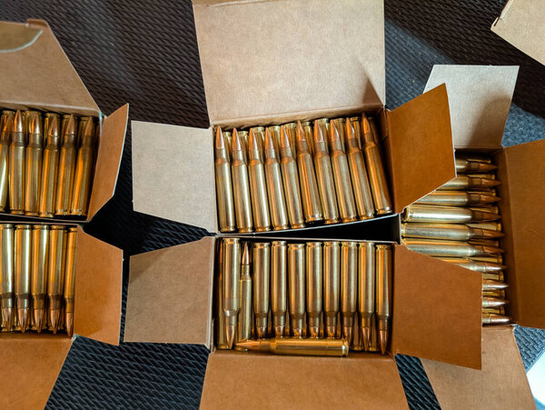 Вид сверху на несколько картонных коробок, заполненных новыми латунными патронами для винтовок, представляющих собой склад для стрельбы по спорту.