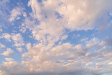 Engin mavi gökyüzünün güzel arkaplanı, tüylü beyaz ve pembe bulutlar manzaralı altın saat günbatımında.