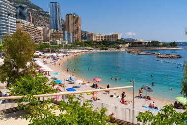 MONTE CARLO, MONACO - 2 Ağustos 2025: Turistler ve yerliler yaz tatili sezonunun en yoğun döneminde kalabalık Larvotto Sahili 'nde güneşli havanın tadını çıkarıyorlar.