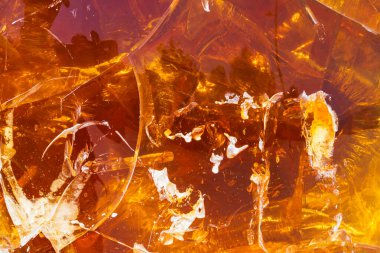 Parlayan turuncu reçine ya da kehribarın soyut makro arkaplanı, şeffaf, karmaşık çatlakları ve sıcak desenleri olan doğal bir madde..