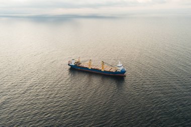 Baltık Denizi 'nin sakin ve açık sularında uçan vinçleri olan genel bir kargo gemisinin insansız hava aracı görüntüsü..