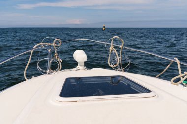 Güneşli bir günde açık denizde yelken açan beyaz bir yatın pruvasından ufka doğru bak..