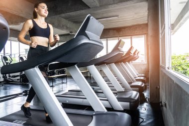 Sevimli genç kadın spor salonunda treadmill egzersiz. Koşu bandı üzerinde çalışan aktif genç kadın. gülümseme ve komik duygu.