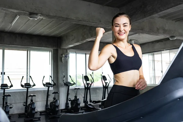 Sevimli genç kadın spor salonunda treadmill egzersiz. Koşu bandı üzerinde çalışan aktif genç kadın. gülümseme ve komik duygu.