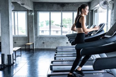 Sevimli genç kadın spor salonunda treadmill egzersiz. Koşu bandı üzerinde çalışan aktif genç kadın. gülümseme ve komik duygu.