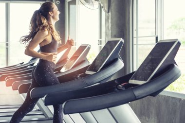 Sevimli genç kadın spor salonunda treadmill egzersiz. Koşu bandı üzerinde çalışan aktif genç kadın. gülümseme ve komik duygu.