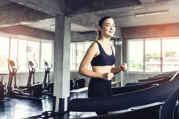 Cute young woman exercising on  treadmill at a gym.Active young woman running on treadmill. smile and funny emotion.