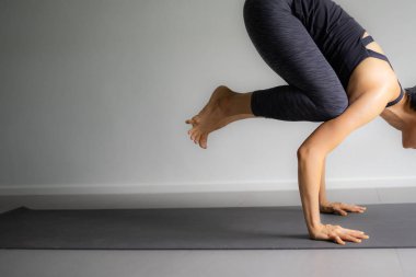 Genç kadın pratik yoga gri arka planda. Gençler yoga kapalı yapmak.