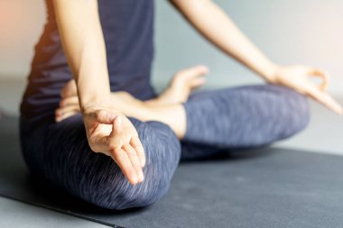 Genç kadın pratik yoga gri arka planda. Gençler yoga kapalı yapıyor. El jest meditasyon içinde kapatın. Kopya alanı.