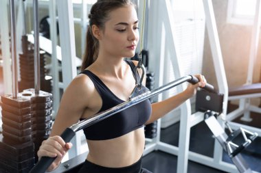 Güzel vücutlu kaslı genç bir kadın halterle egzersiz yapıyor. Sportif kız spor salonunda ağırlık kaldırıyor..