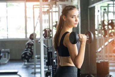 Güzel vücutlu kaslı genç bir kadın halterle egzersiz yapıyor. Sportif kız spor salonunda ağırlık kaldırıyor..