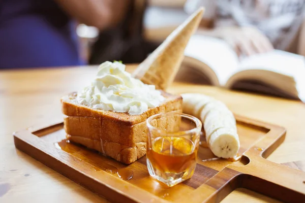 Honey bread with caramel syrup and fresh cream.Ice cream and banana slice with bread on plate.