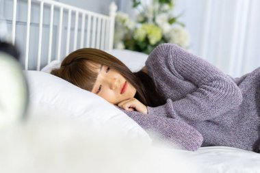 Kadın yatakta arkadan görünüm, uyanma sonra germe. Büyük beyaz pencere sırasında germe yatağa geri sabah güneş doğarken ile uyanma sonra görünümü oturan kadın.