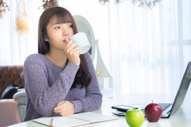 Penceresinden bir fincan kahve açık renkli ellerinde tutan Asyalı kadın. O kazak menekşe renkli elbise. Sabah kahvesi saat.