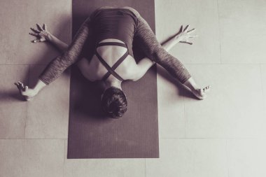 Genç kadın pratik yoga gri arka planda. Gençler yoga kapalı yapıyor. Güzel genç fitness kadının çalışma dışarı üstten görünüm .