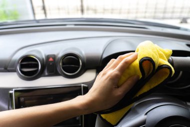 Bir adam sarı mikrofiber bezle beyaz araba Temizleme.