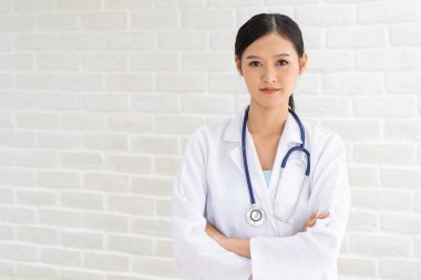Portre portre, gülümseyen güzel kadın Asyalı doktor kollarını ile ayakta geçti. Tuğla zemin üzerine ilaç temsilcisi kavramı.